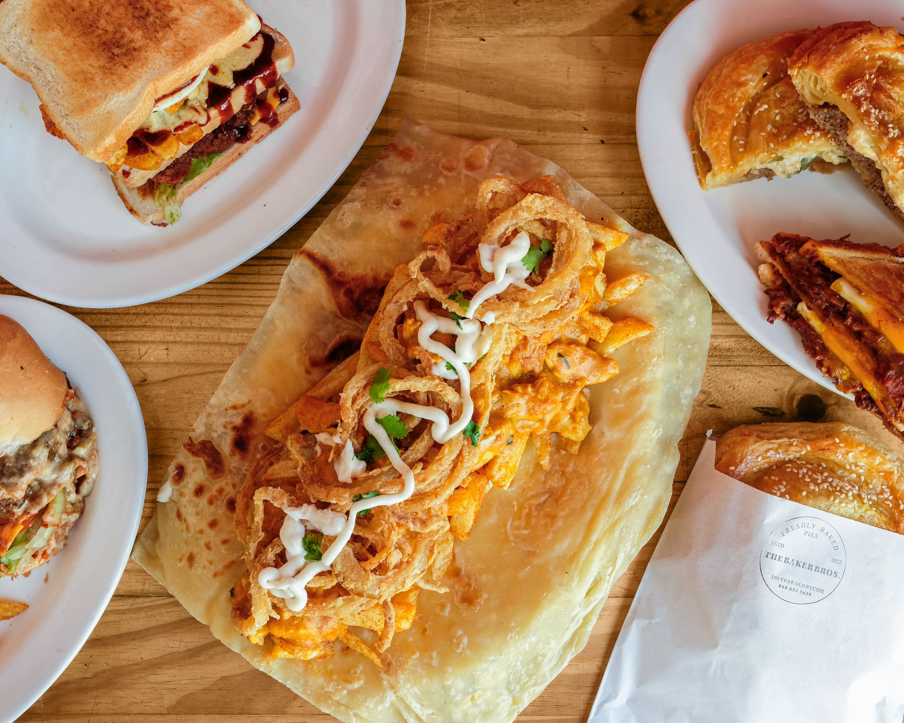A spread of Baker Bros. take-away dishes including toasties, burgers and pies